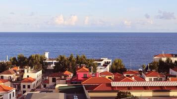 Una piscina en la azotea con vista al mar y edificios circundantes.