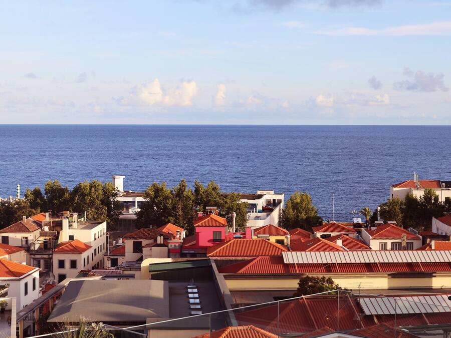 Una piscina en la azotea con vista al mar y edificios circundantes.