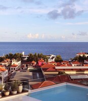 A rooftop pool with a view of the sea and surrounding buildings.