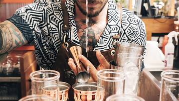 A person preparing drinks in a bar setting with multiple glasses and bottles.