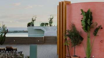 Una terrazza sul tetto con vista sul mare, caratterizzata da un pavimento in legno, una zona salotto e piante in vaso.