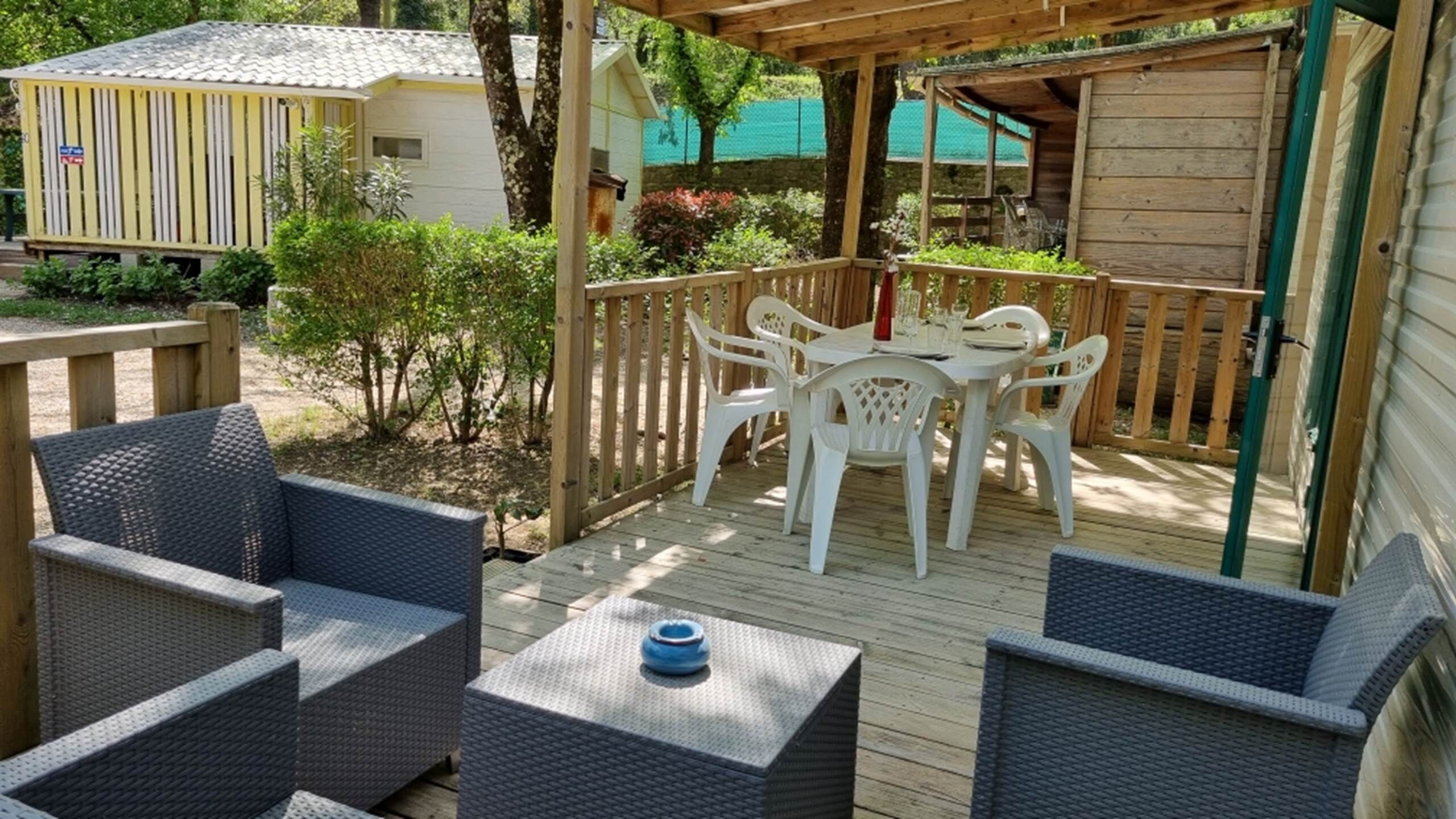 Eine überdachte Terrasse mit Korbmöbeln und einem für das Essen gedeckten Tisch.
