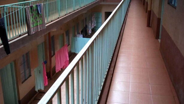 Ein mehrgeschossiges Treppenhaus mit Balkonen, Fliesenböden und aufgehängter Wäsche.