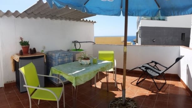 A terrace with a table, chairs, and a blue umbrella. - Casa Mari Playa De Mogan (Mogan)