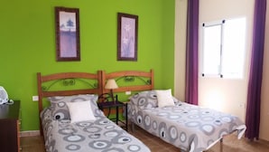 A room with two beds, green walls, and a window with purple curtains. - Casa Mari Playa De Mogan (Mogan)