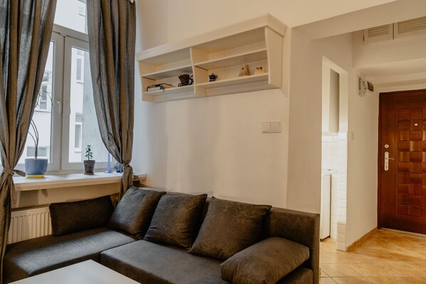 A modern living room with a sectional sofa, a window with curtains, and built-in shelves with decorative items.