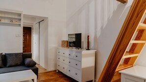 A modern living room with a white sofa, a white dresser, and a wooden staircase. - Warsaw Concierge Loft Chmielna (Warsaw)