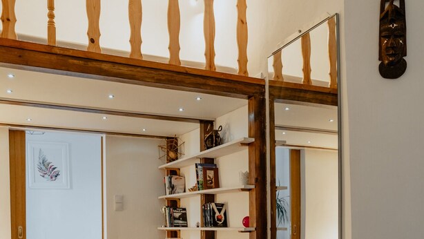 A room with a wooden floor, a white table, a bookshelf, and a bed with a white headboard. - Warsaw Concierge Loft Chmielna (Warsaw)