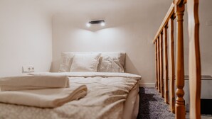 A bedroom with a bed, a wooden staircase, and a wall-mounted light fixture. - Warsaw Concierge Loft Chmielna (Warsaw)