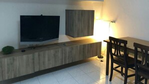 Eine moderne Küche mit integriertem Fernseher, Holzschränken, einem Esstisch mit Stühlen und einer Stehlampe.