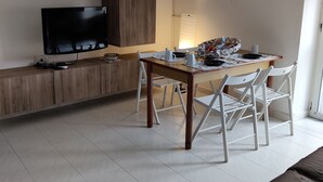 Eine moderne Küche mit Flachbildfernseher, Holzschränken, einem Esstisch mit Stühlen und einer Pendelleuchte.