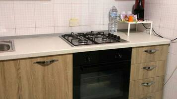 Een keuken met een gasfornuis, oven, houten kastjes en een betegelde spatwand.