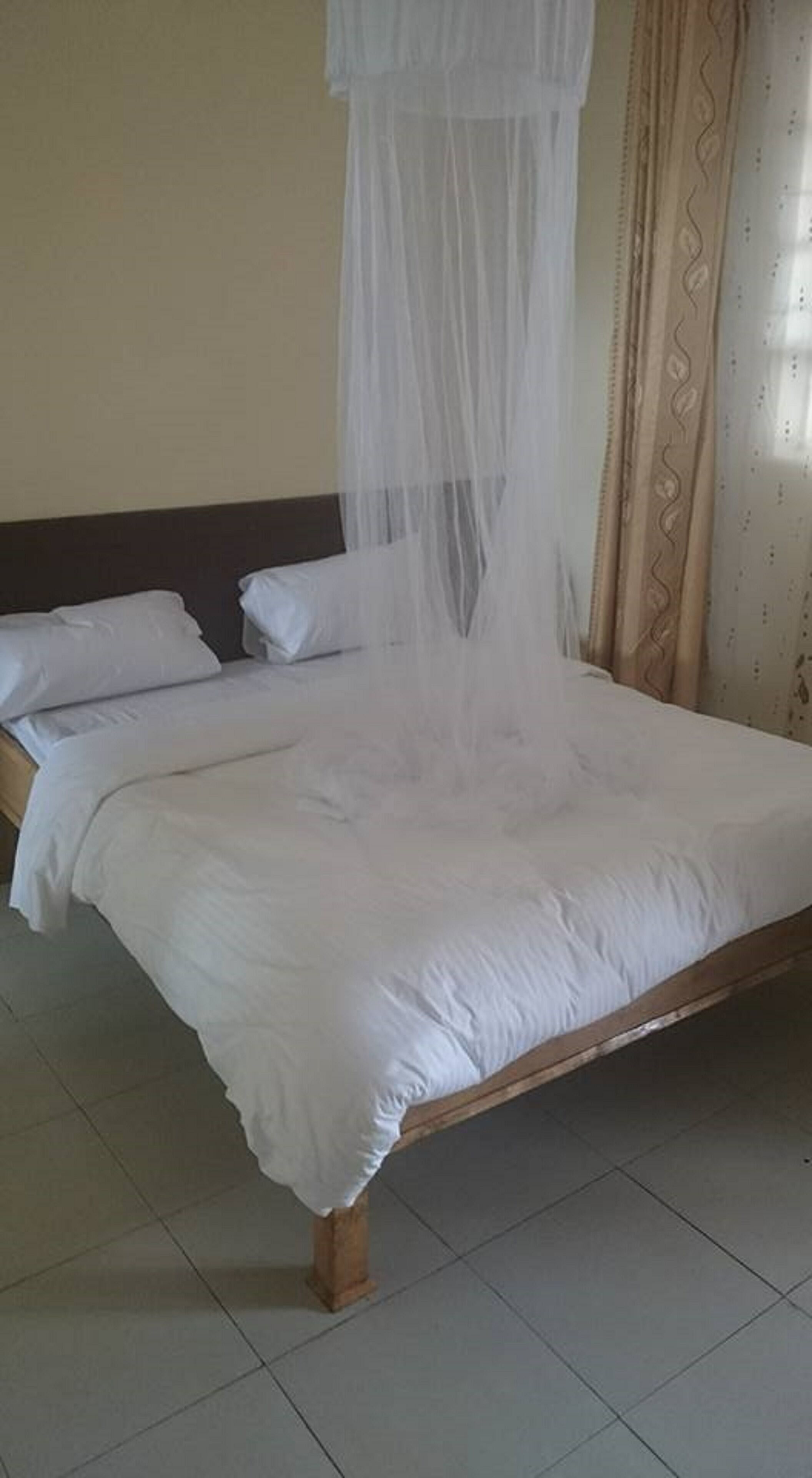 A bed with a canopy, white bedding, and a wooden headboard.