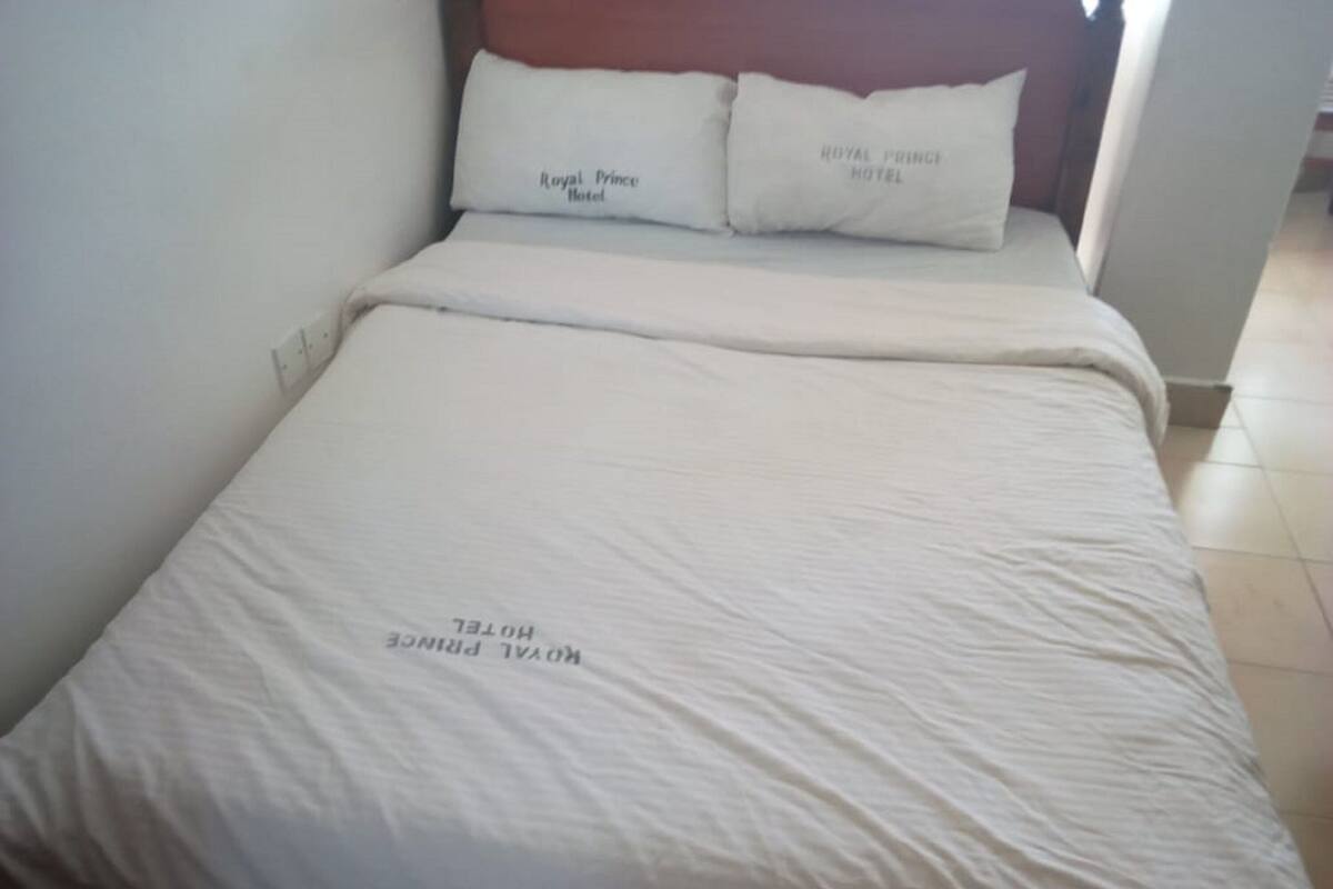 A bed with white bedding and pillows labeled 'Royal Prince Hotel.'