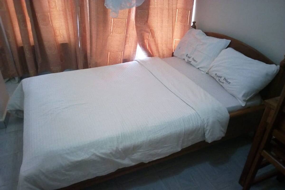 A single bed with white bedding, a wooden headboard, and a nightstand.