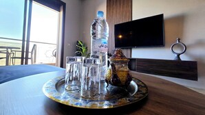 A table with a tray of glasses, a bottle of water, and a decorative item in a room with a TV and a window. - Apartment Bagatelle (Marrakech)