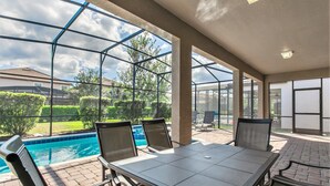 Ein überdachter Außenbereich mit Pool, Sitzgelegenheiten und Blick auf die umliegende Landschaft.