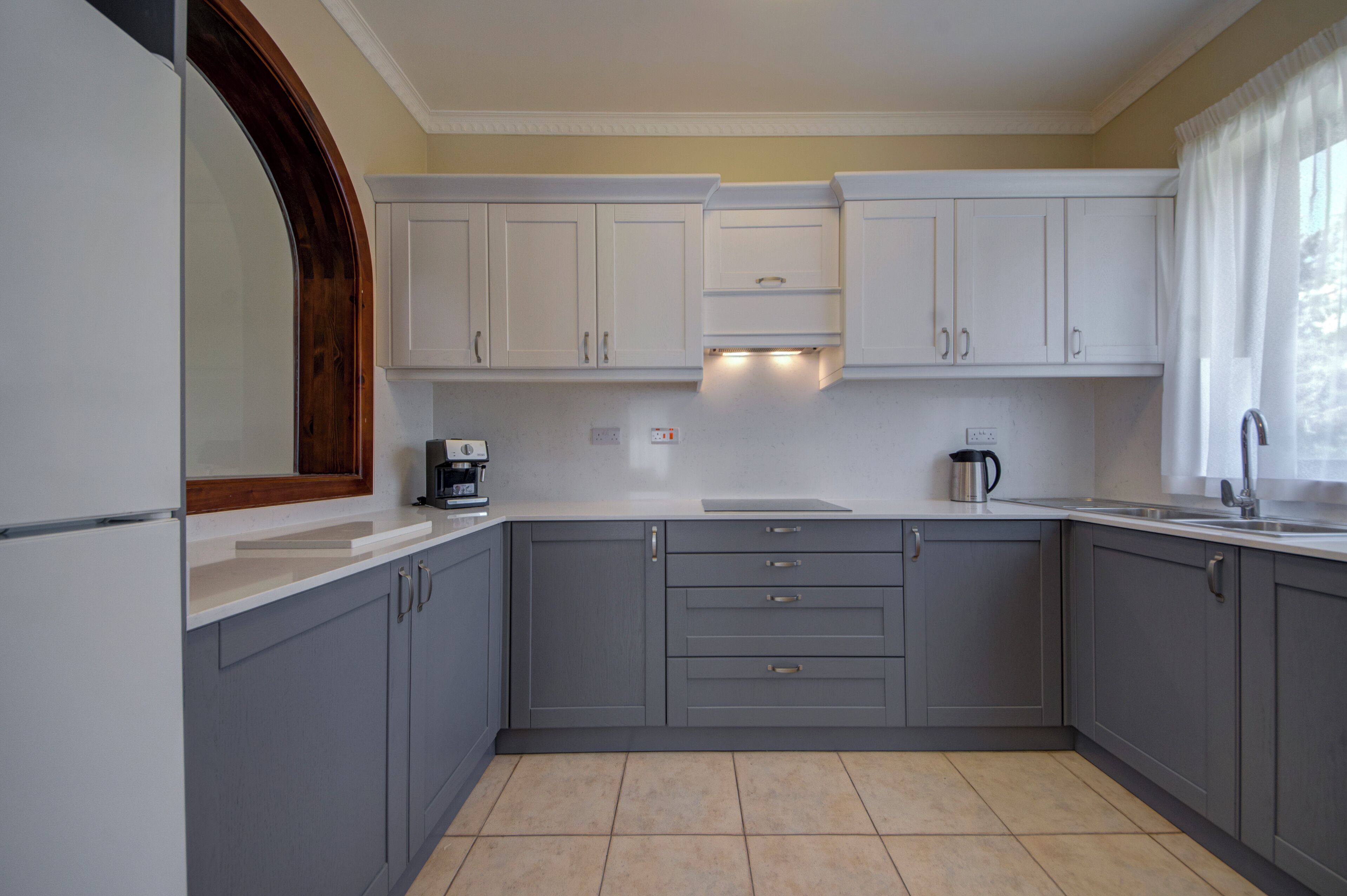 A kitchen with grey cabinets, a white countertop, and a built-in oven.
