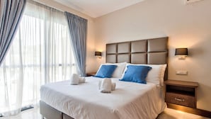 A neatly made bed with white and blue pillows, a headboard, and a nightstand with a lamp.