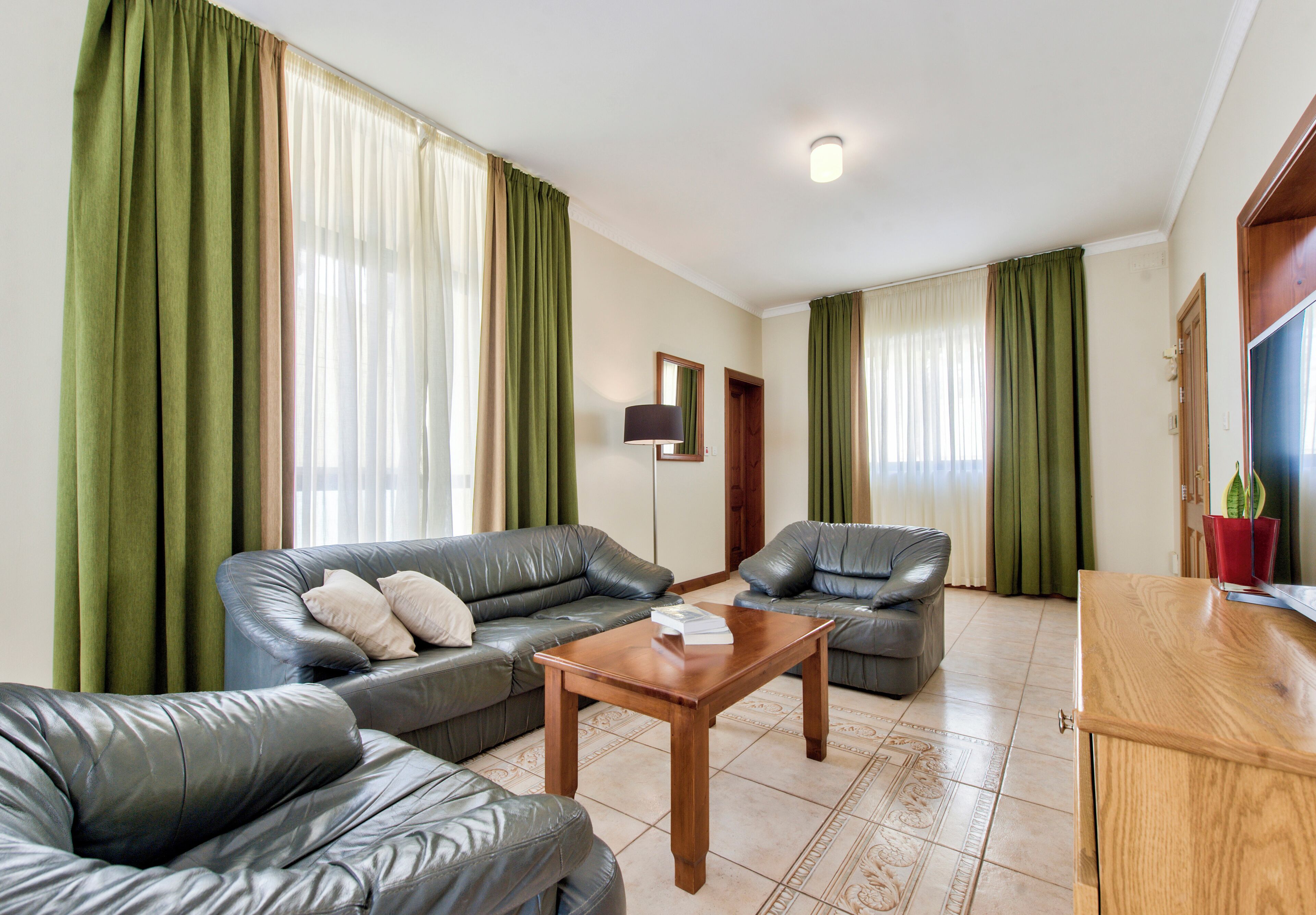 A living room with a sofa set, a coffee table, and curtains.