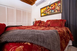 Quarto com cama grande, um quadro na parede e janela com cortinas.