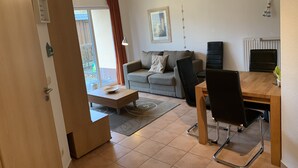 Una sala moderna con un sofá gris, una mesa de centro de madera y un comedor con una mesa y sillas.