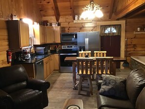Un intérieur chaleureux de chalet en bois, comprenant une cuisine, un coin repas et un espace détente.