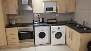 A compact kitchen with a Bosch oven, a Samsung washing machine, a microwave, and a toaster. - Luxury, comfortable and secure home away from home for the best JHB experience (Sandton)