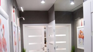 Un pasillo con puertas blancas, piso de baldosas y cuadros enmarcados en las paredes.