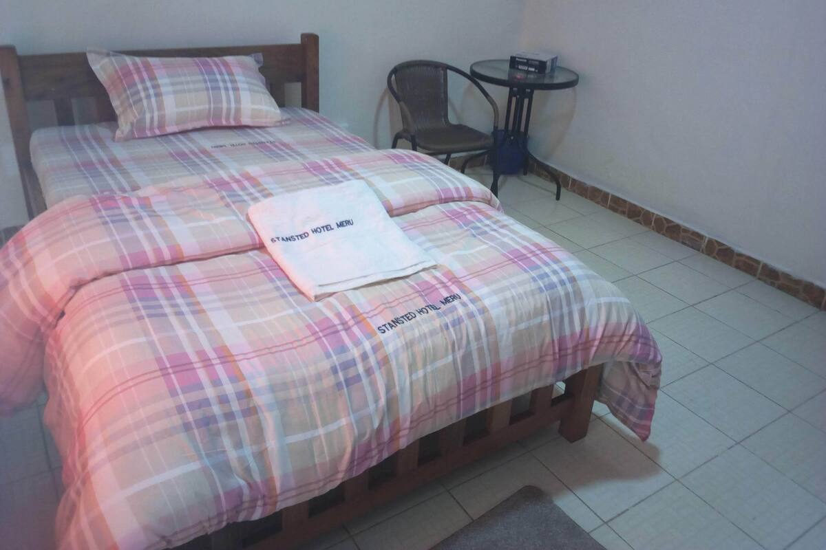 Una cama bien hecha con una colcha escocesa y un menú doblado encima.