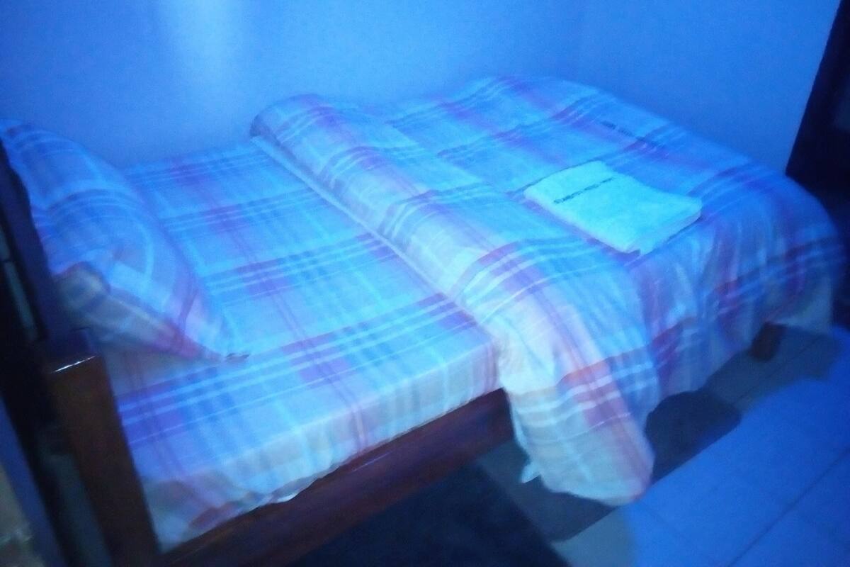 Una cama con una colcha escocesa y una almohada blanca.