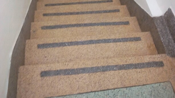 A staircase with a star-shaped mat at the top and a textured mat at the bottom. - Stansted Annex Hotel (Meru)