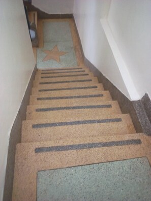 A staircase with a star-shaped mat at the top and a textured mat at the bottom. - Stansted Annex Hotel (Meru)