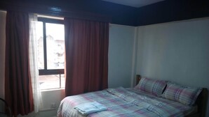 A bedroom with a bed, a chair, and a window with curtains. - Stansted Annex Hotel (Meru)