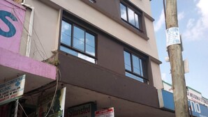 A multi-story building with various commercial establishments on the ground floor, including a gaming arcade, a mobile repair shop, and a store named 'Celb Electronics'. - Stansted Annex Hotel (Meru)