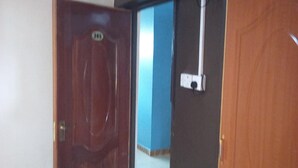 A room with a wooden door, a blue wall, and a tiled floor. - Stansted Annex Hotel (Meru)