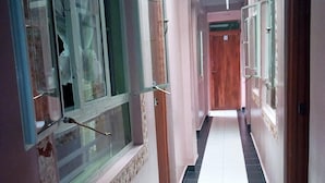 Un couloir doté d’un sol carrelé, de portes en bois et d’une lucarne.