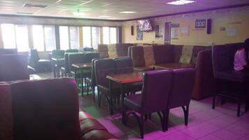 A restaurant with booths and tables, a tiled floor, and a television on the wall.