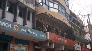 Un immeuble à plusieurs étages abritant un hôtel appelé « STEMUKI HOTEL » au dernier étage, une succursale bancaire à l’étage inférieur et une antenne du centre de soins « We Trust ».