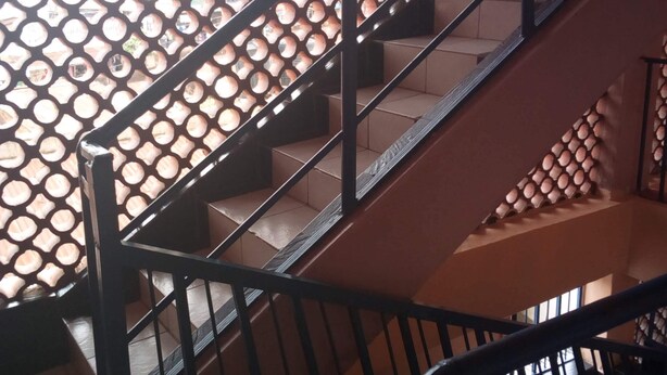 Un escalier avec un mur orné de motifs et des rampes en métal.