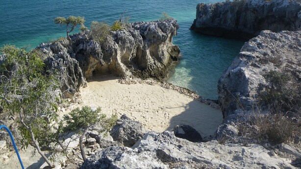 A coastal landscape with rocky formations, clear blue water, and sparse vegetation. - Manga Lodge (Andavadoaka)