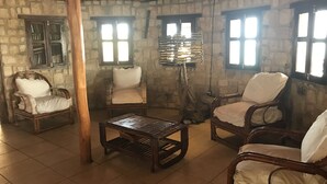 A rustic room with stone walls, wooden furniture, and a tiled floor. - Manga Lodge (Andavadoaka)