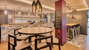Un espace bar comprenant un comptoir, plusieurs tabourets de bar et une table ronde avec des chaises.