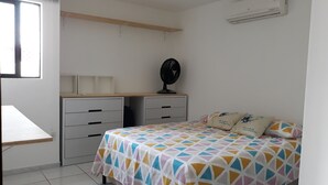 A bedroom with a bed, a desk, and a chair. There is an air conditioning unit on the wall. - APARTMENT ON THE BEACH (Bessa)