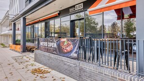 Un bâtiment moderne avec une enseigne indiquant « BAR+BLOCK STEAKHOUSE » et une banderole annonçant « NOUS SOMMES OUVERTS ».