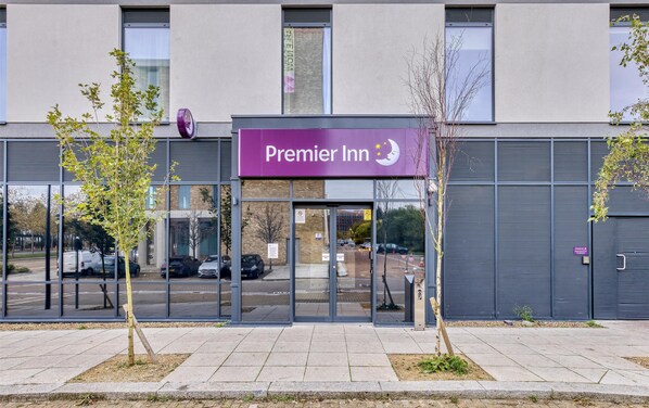 L’entrée d’un hôtel Premier Inn, avec une façade moderne, de grandes fenêtres et une vue dégagée sur le parking.
