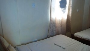 A single bed with a canopy, a bedside table, and a power outlet on the wall. - Sunset Guest House (Meru)