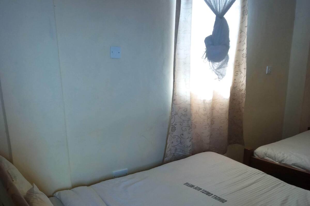Una cama individual con dosel, una mesita de noche y un enchufe en la pared.