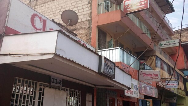 A multi-story building with various commercial establishments on the ground floor, including a guest house and a milk shop. - Sunset Guest House (Meru)