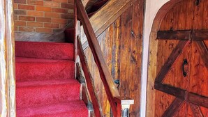 A wooden staircase with red carpeted steps leading to a door with a large wooden panel. - 5 bedroom accommodation in Elmer, near Bognor Regis (Elmer, near Bognor Regis)